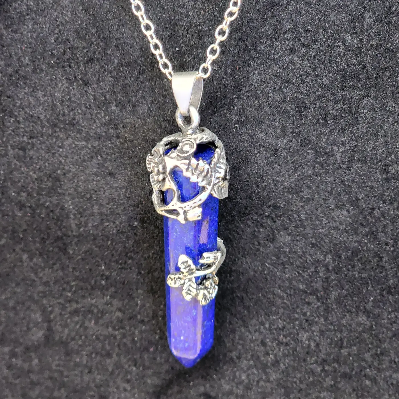A lapis lazuli crystal point pendant on a silver chain