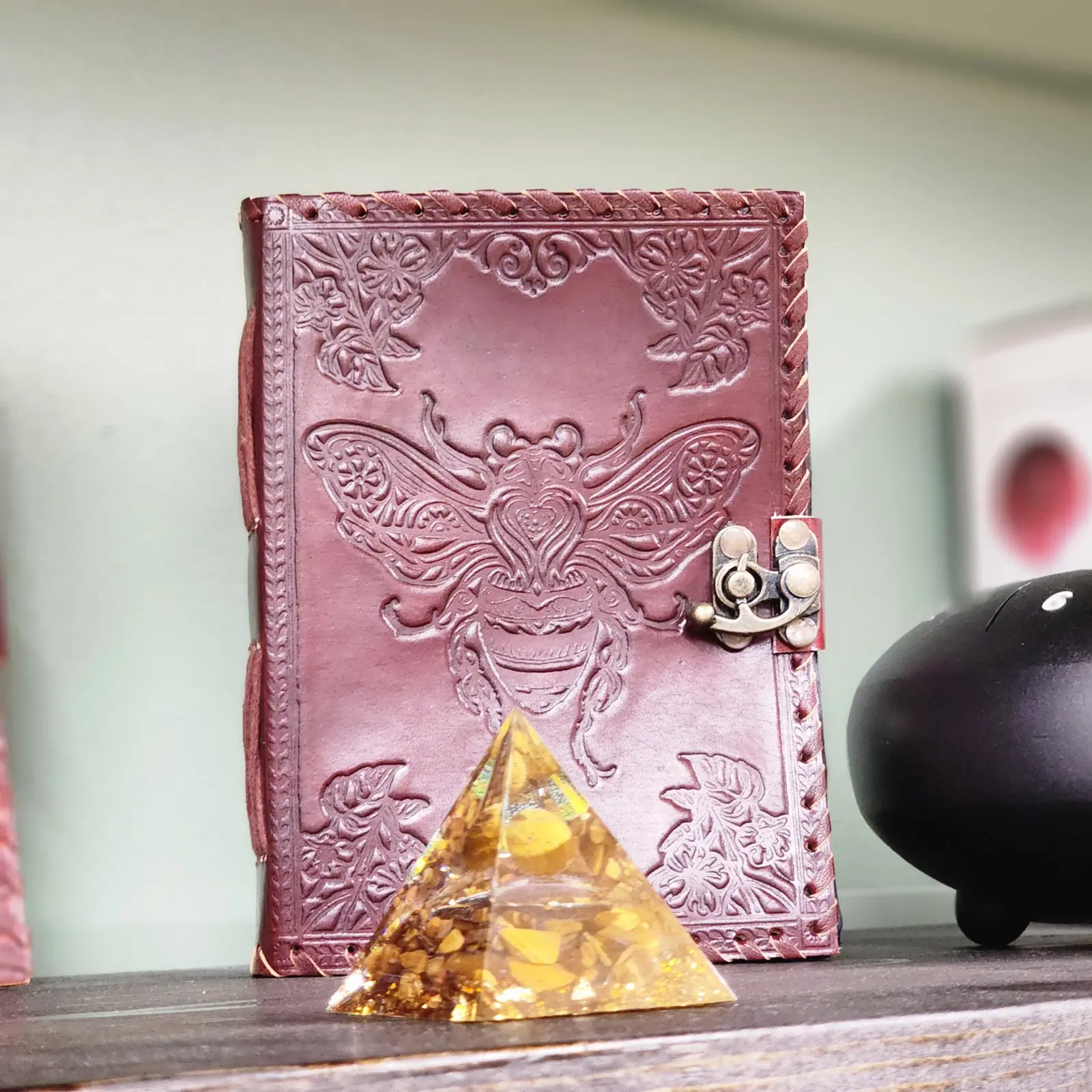 A tooled leather journal beside an orgone pyramid