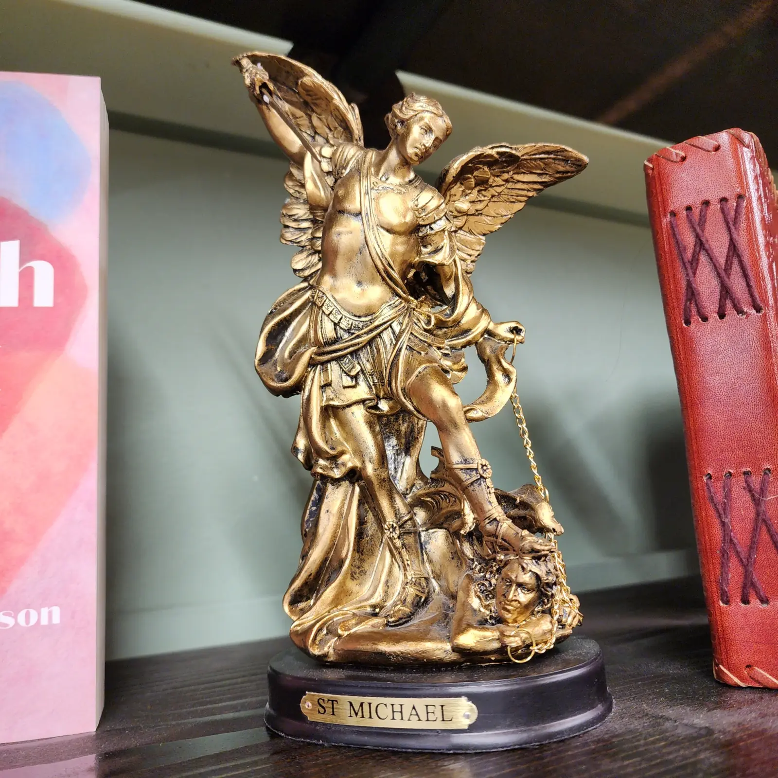 A St. Michael statue and journals on a shelf